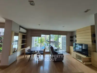 Spacious living room with modern decor and large windows opening to a balcony with a view.