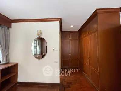 Spacious bedroom with elegant wooden built-in wardrobes and parquet flooring.