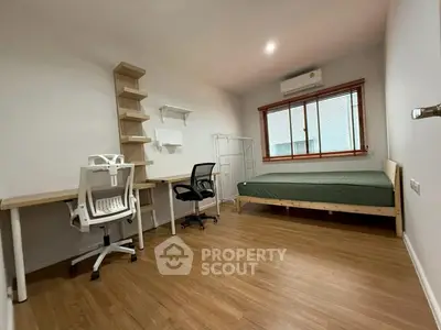 Modern minimalist bedroom with wooden flooring, study desk, and air conditioning.
