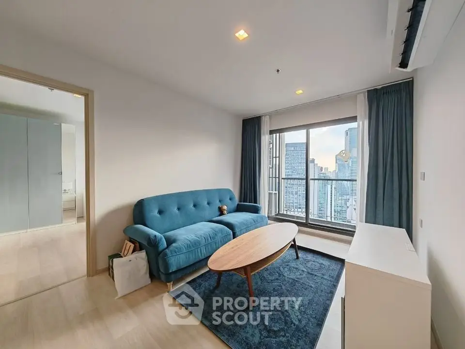 Modern living room with city view, featuring a stylish blue sofa and sleek wooden furniture.
