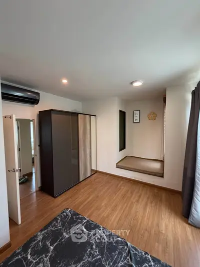 Spacious bedroom with modern wardrobe and wooden flooring, featuring a cozy nook and ample natural light.