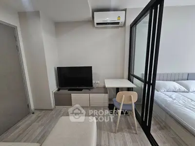 Modern studio apartment with sleek design, featuring a cozy living area and a comfortable bedroom separated by glass partition.