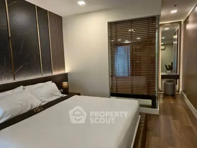 Luxurious modern bedroom with elegant decor and wooden flooring, featuring a cozy bed and stylish lighting.