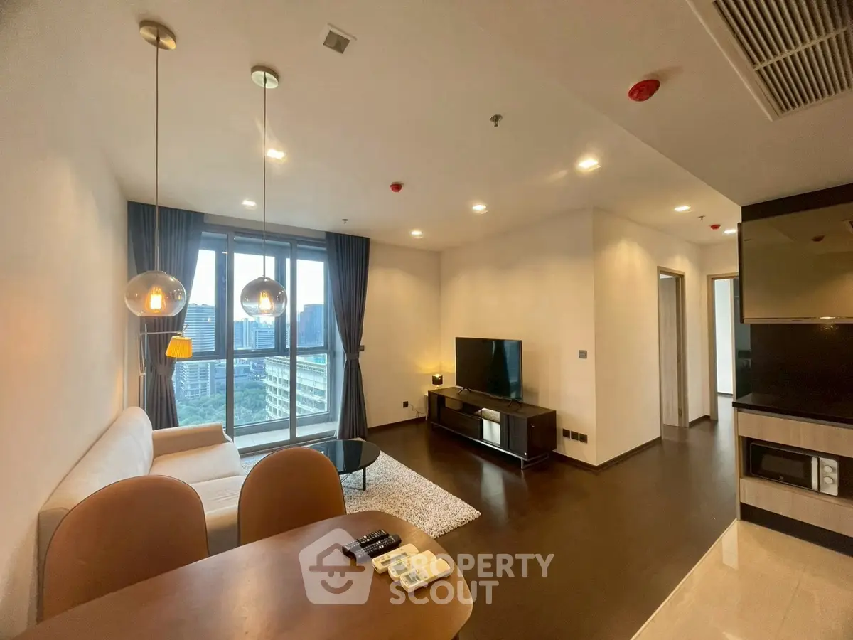Modern living room with large windows and city view, featuring stylish furniture and sleek design.