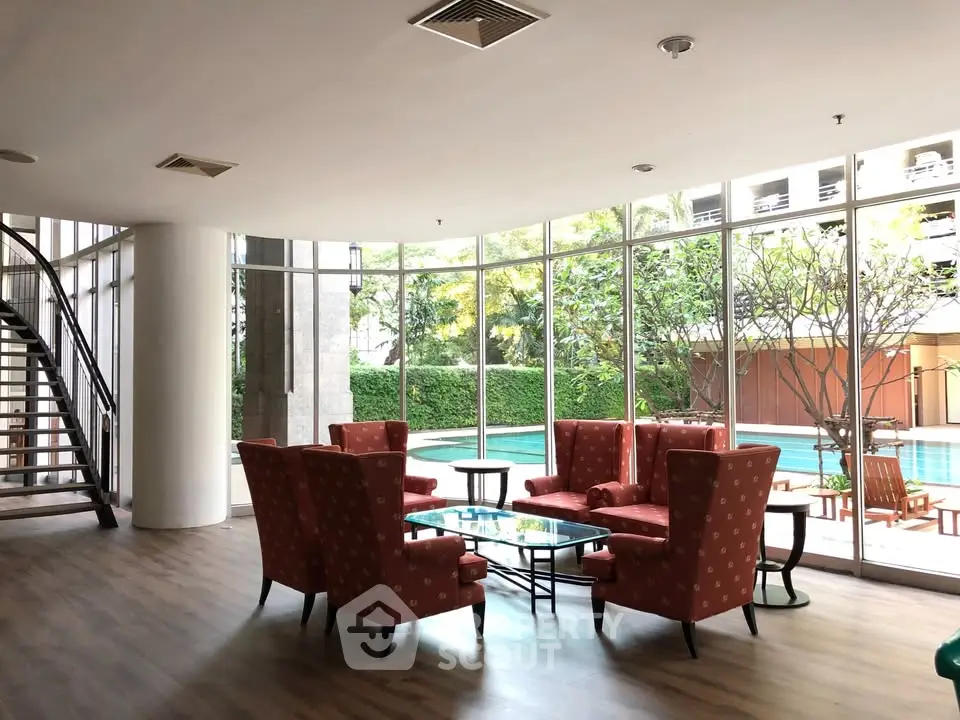 Luxurious poolside lounge with elegant seating and glass walls offering serene garden views.