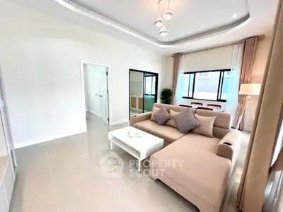 Spacious modern living room with elegant beige sofa and large windows.