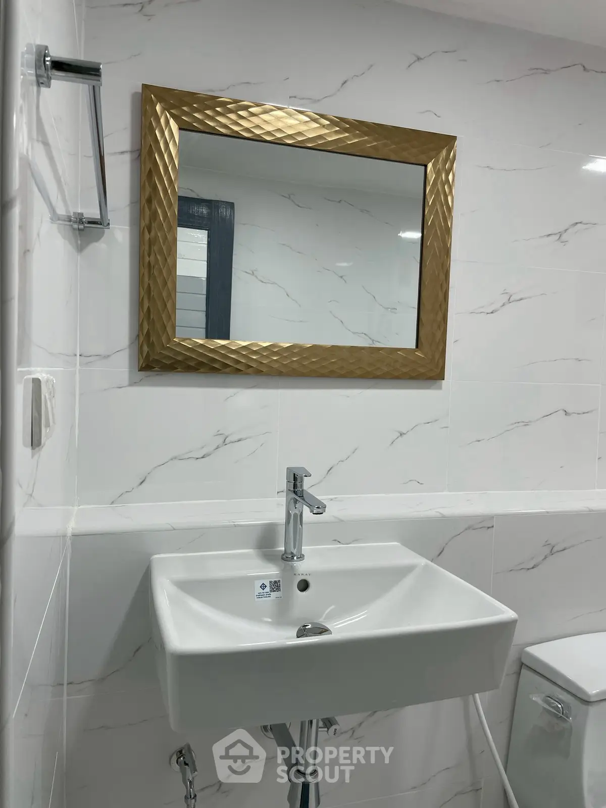 Modern bathroom with elegant gold-framed mirror and sleek white sink.