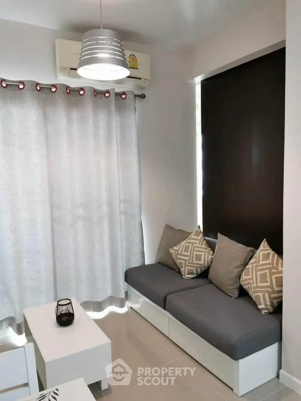 Modern living room with cozy seating and stylish decor, featuring air conditioning and elegant lighting.
