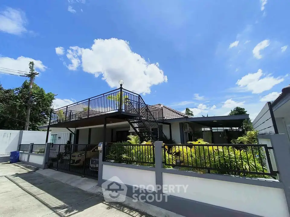 Charming single-story home with rooftop terrace and lush garden under clear blue sky.