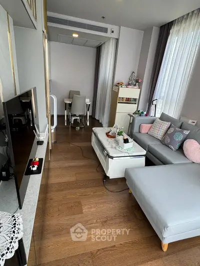 Modern living room with stylish decor and wooden flooring, featuring a cozy sectional sofa and a sleek TV setup.