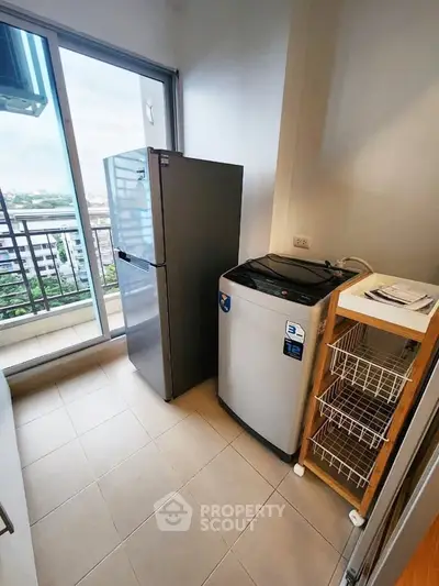 Modern condo laundry area with washing machine and fridge, offering city views from the balcony.