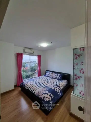 Spacious bedroom with large window and scenic view, featuring elegant decor and wooden flooring.