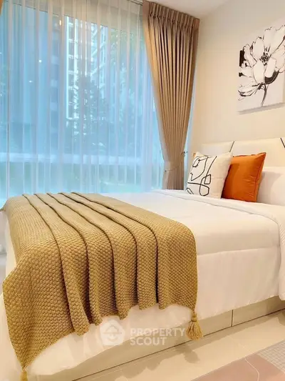 Cozy bedroom with modern decor and large window offering natural light.
