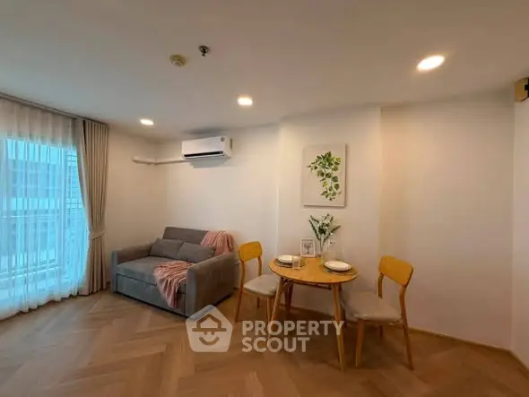 Cozy living room with modern decor and natural light, featuring a small dining area and stylish furnishings.