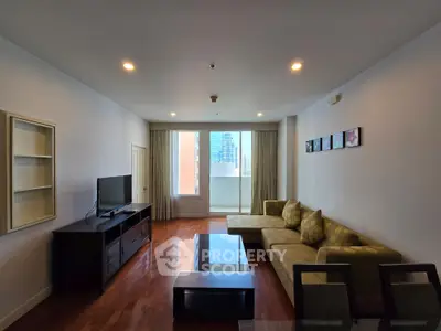 Spacious living room with modern decor and city view, featuring a comfortable sectional sofa and entertainment unit.