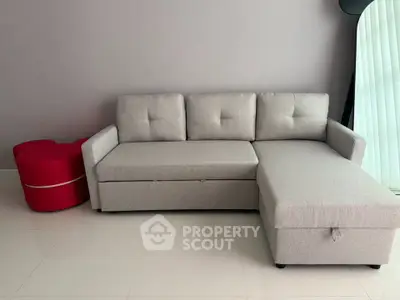 Modern living room with stylish gray sectional sofa and vibrant red accent chair.