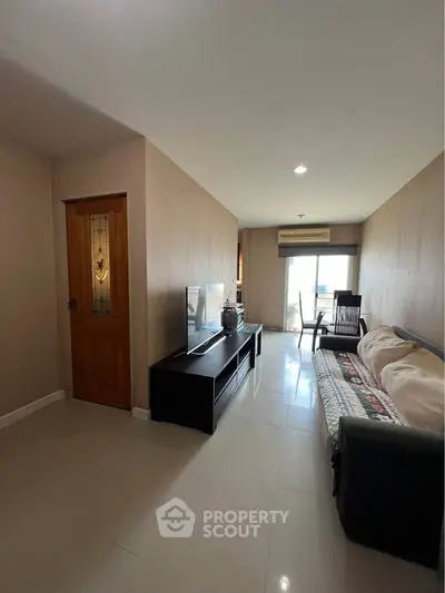 Spacious living room with modern decor and natural light, featuring a cozy sofa and entertainment unit.