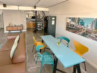 Stylish open-plan living room with modern furniture and spiral staircase in urban apartment.