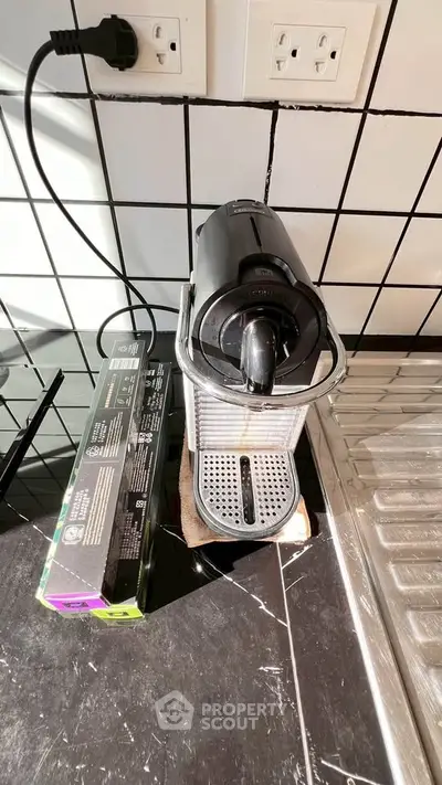 Modern kitchen corner with espresso machine and sleek black tiles
