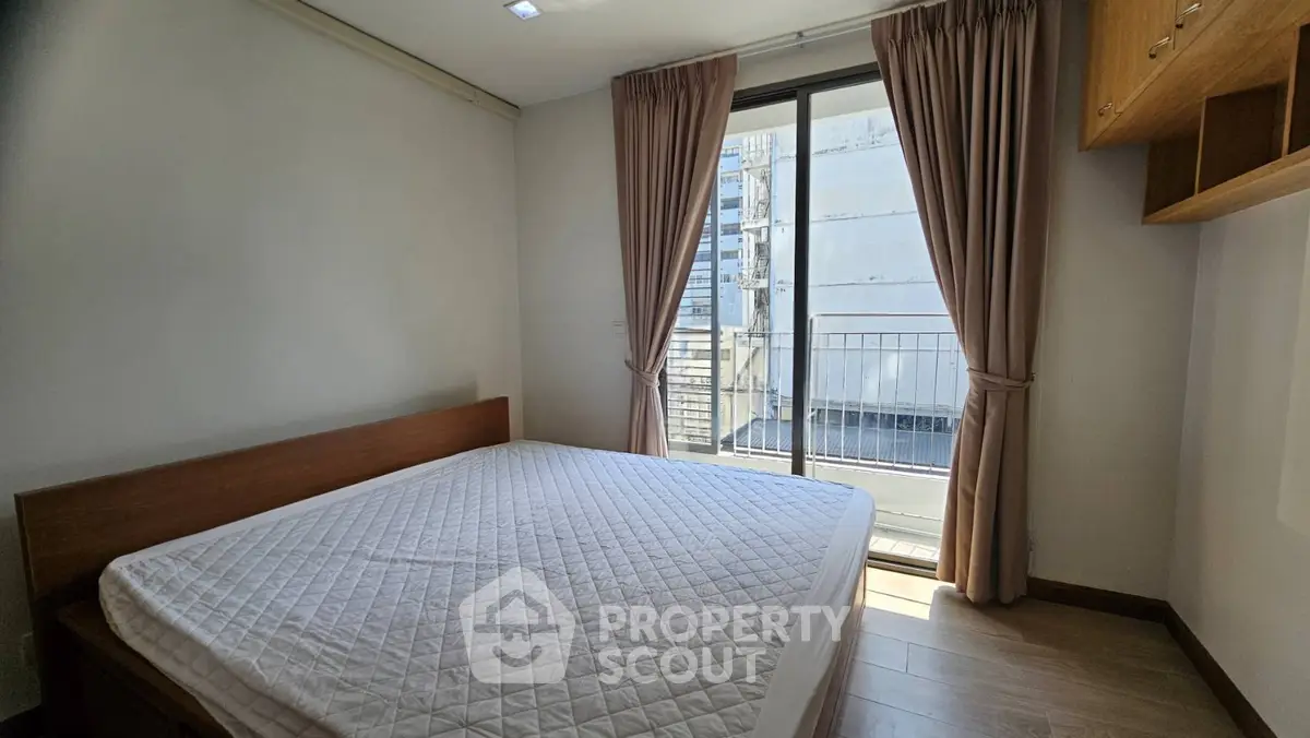 Bright bedroom with large window and balcony access in modern apartment