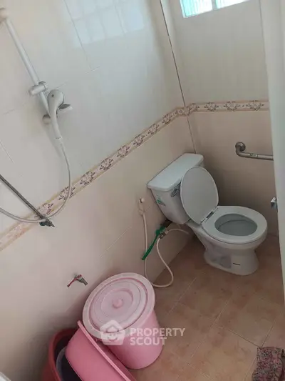 Compact bathroom with shower and toilet, featuring a simple design and neutral tiles.