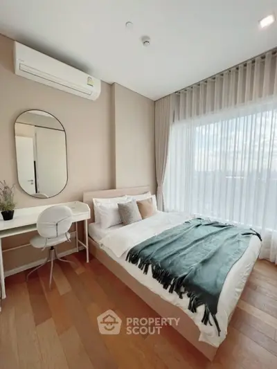 Modern bedroom with stylish decor, large window, and cozy workspace.