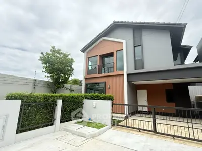 Modern two-story house with sleek design and spacious driveway in a suburban neighborhood.