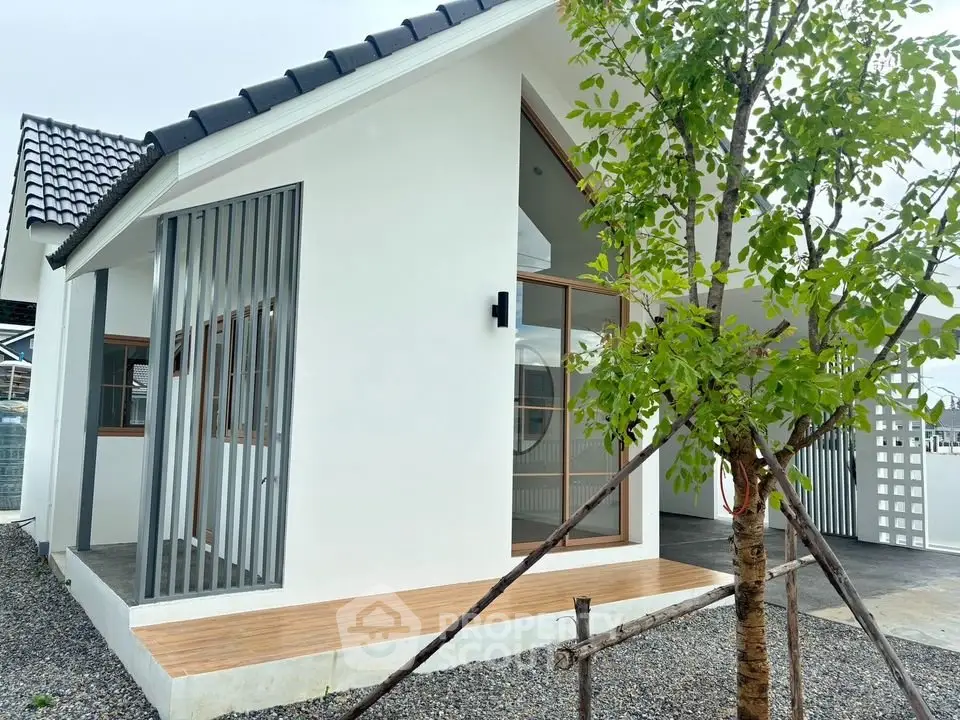 Modern minimalist white house with sleek design and tree in front yard.