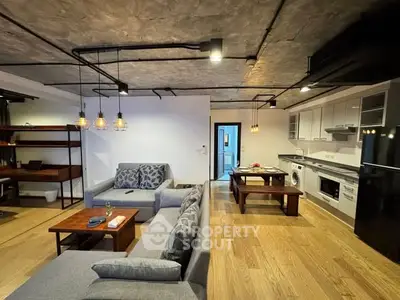 Spacious modern living room with open kitchen, stylish lighting, and cozy seating area.