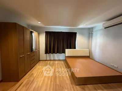 Spacious bedroom with wooden flooring and modern furniture