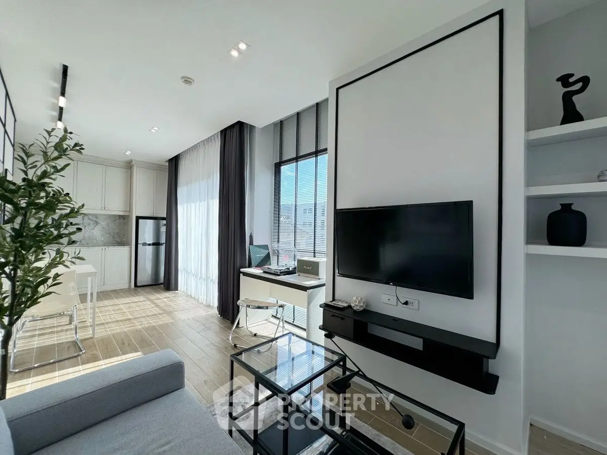 Modern living room with open kitchen, sleek decor, and abundant natural light.