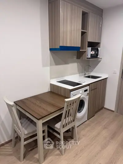 Modern compact kitchen with integrated appliances and dining area in a stylish apartment.