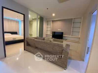 Modern living room with cozy sofa and TV, adjacent to a stylish bedroom in a contemporary apartment.