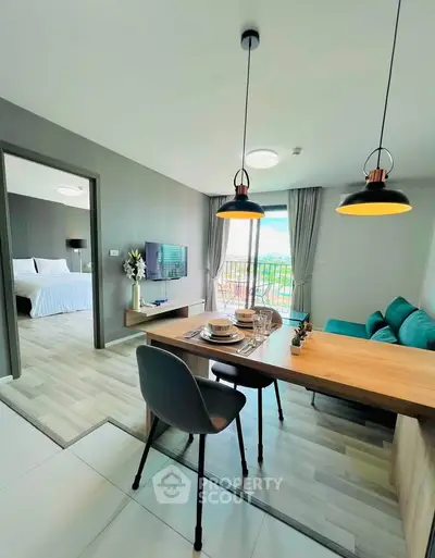 Modern open-plan living room with dining area and view of bedroom, featuring stylish decor and natural light.