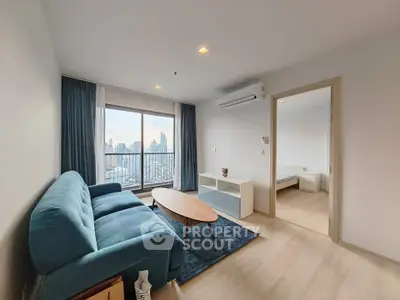 Modern living room with city view, blue sofa, and wooden coffee table in a high-rise apartment.