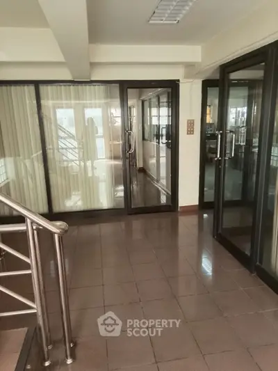 Spacious office entrance with glass doors and tiled flooring, ideal for professional settings.