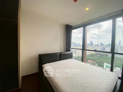 Modern bedroom with stunning city view from large windows in high-rise apartment.