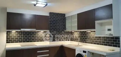 Modern kitchen with dark wood cabinets, black tile backsplash, and built-in appliances.