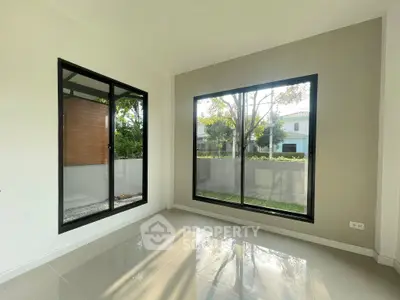 Bright and spacious room with large windows and garden view, perfect for modern living.
