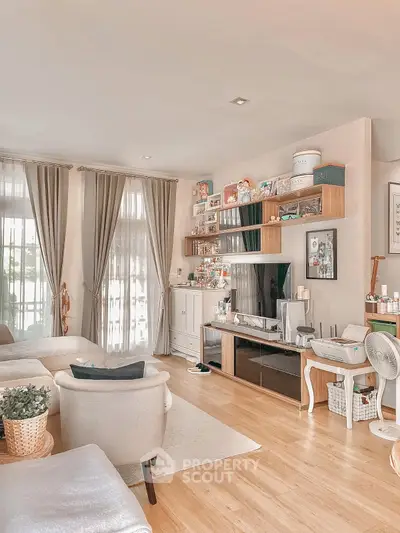 Charming living room with elegant decor and natural light, featuring cozy seating and stylish shelving.
