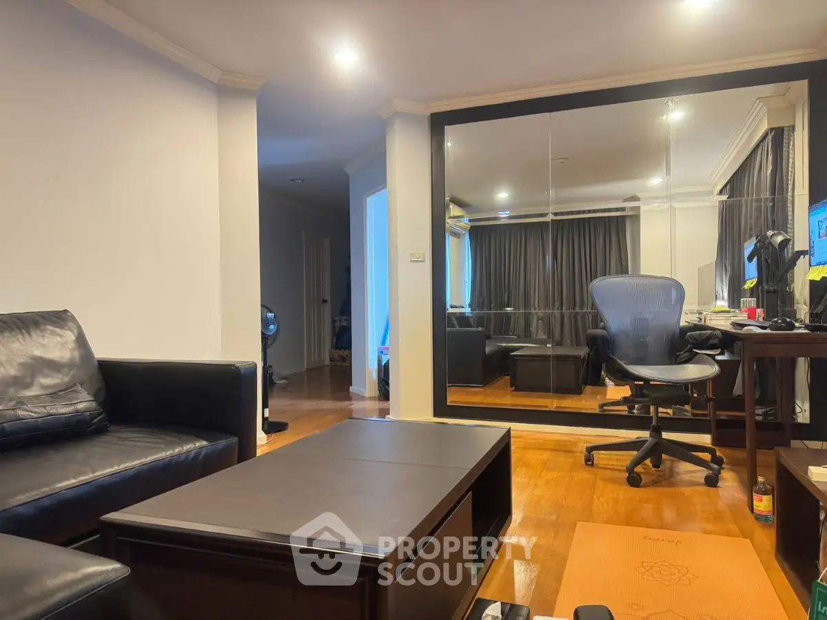 Modern living room with sleek black furniture and mirrored wall for spacious feel.