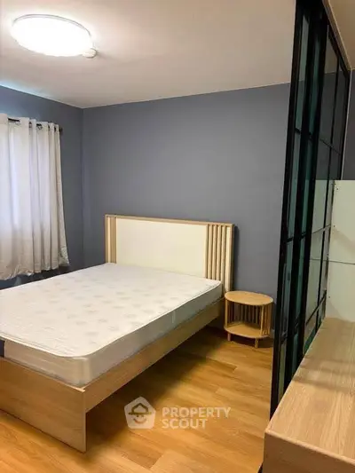 Modern bedroom with wooden flooring and stylish bed frame in a cozy apartment.
