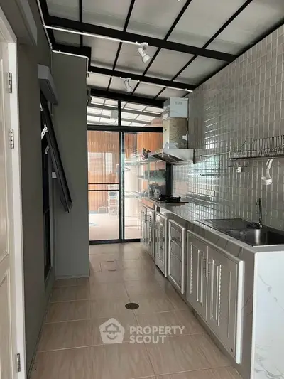 Modern kitchen with sleek cabinetry and tiled backsplash, featuring an open layout and ample natural light.