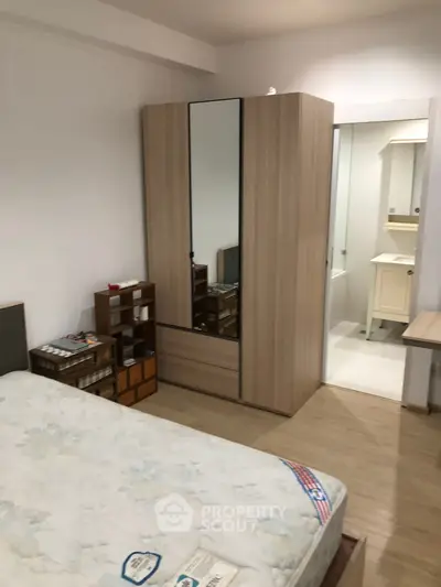 Cozy bedroom with wooden wardrobe and adjacent bathroom, ideal for comfortable living.