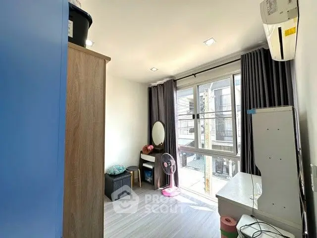 Bright bedroom with large window, modern furnishings, and air conditioning unit.