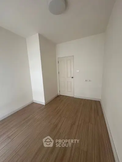 Minimalist empty room with wooden flooring and white walls, ready for customization.