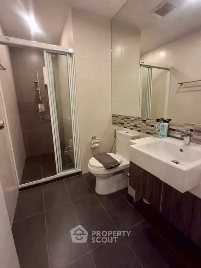 Modern bathroom with sleek shower and stylish sink in contemporary apartment.