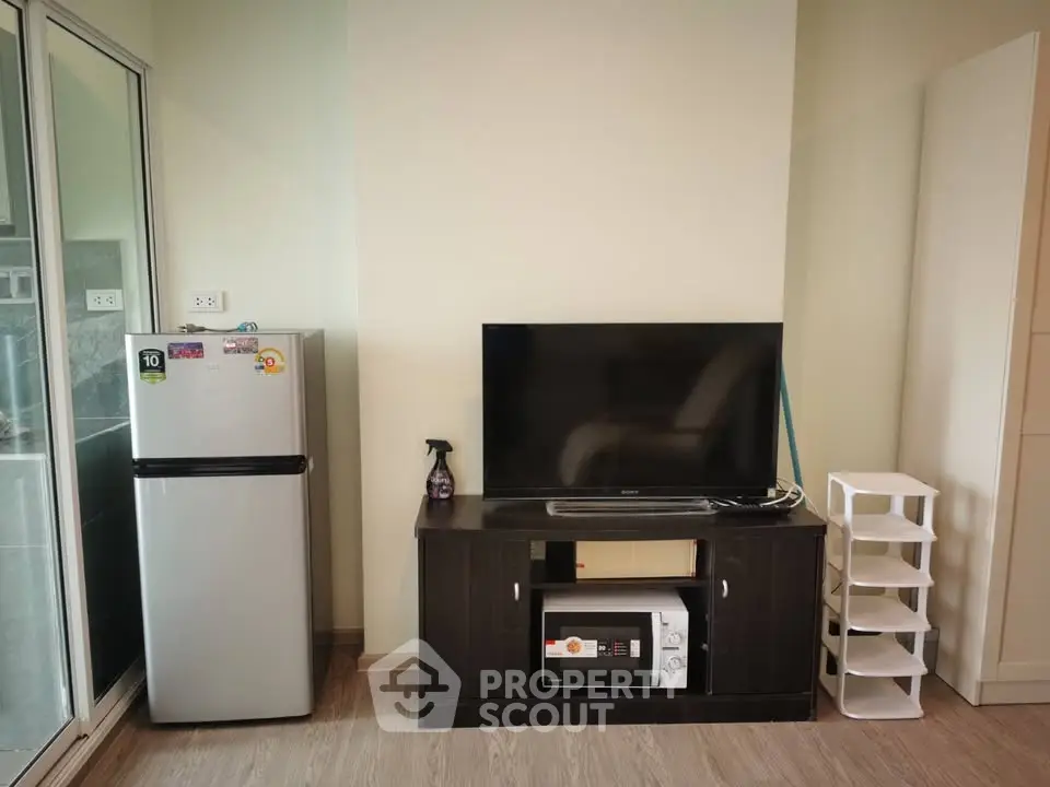 Modern living room with sleek TV stand, refrigerator, and microwave in stylish apartment.