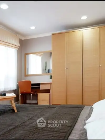 Cozy bedroom with wooden wardrobe and study desk, perfect for relaxation and productivity.