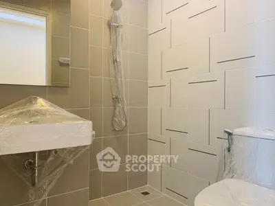 Modern bathroom with sleek tiles and a stylish showerhead, showcasing contemporary design.